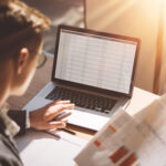 Young banking finance analyst in eyeglasses working at sunny office.